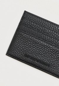 Portofel pentru carduri din piele texturată neagră, cu logo-ul Emporio Armani embossat și mai multe sloturi pentru carduri pe un fond deschis.