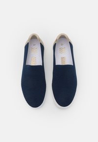 Baskets à enfiler bleu marine avec une tige en tissu texturé, une bordure beige au col et une semelle en caoutchouc blanche. Taille 37 indiquée à l'intérieur.