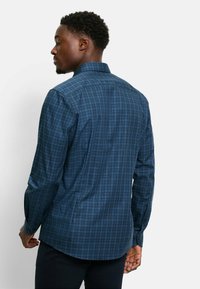 Herrenhemd im dunkelblauen Karomuster, mit klassischem Kragen, langen Ärmeln und abgerundetem Saum, aus strukturiertem Baumwollstoff gefertigt.