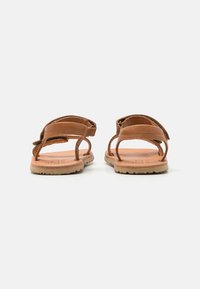 Bruna lädersandaler med öppen design, justerbara remmar och strukturerade gummisulor, som har en mjuk fotbädd för komfort.