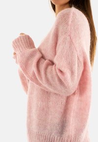 Maglione a maglia rosa chiaro con vestibilità rilassata, polsini a costine e texture leggermente trasparente, caratterizzato da un collo a barca e spalle scese.