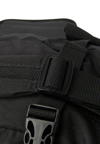 Zwarte nylon rugzak met verstelbare webbing schouderbanden, een gesp sluiting en een textuur oppervlak met versterkte stiksels.