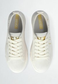 Sneaker bianchi realizzati in tessuto testurizzato con una finitura morbida, dotati di lacci, un accento dorato sulla linguetta e una soletta con marchio.