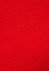 Tissu rouge avec une texture côtelée diagonale uniformément espacée créant des lignes parallèles en relief sur la surface.