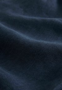 Marineblåt stof med en glat, let blank tekstur, der har subtile variationer i væv og minimal lysrefleksion.