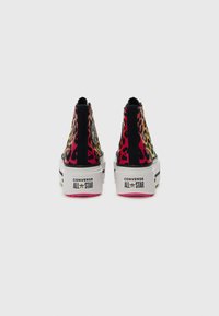High-top sneakers featuring a vibrant animal print in pink, yellow, and black, with a black accent and a white textured sole.