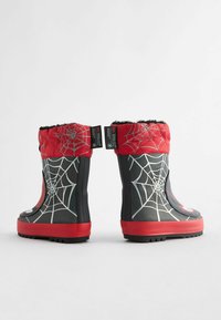 Bottes de pluie en caoutchouc noir avec un dessus matelassé rouge, motif toile d'araignée et une semelle rouge. Intérieur doublé en fausse fourrure noire pour l'isolation.