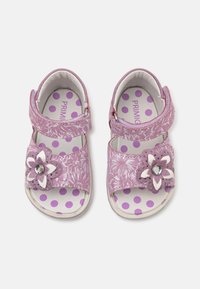 Lilla barne sandaler med blomstermønster, stroppelukking og innleggssåler med prikker. Pyntet med en blomst med en rhinestone.