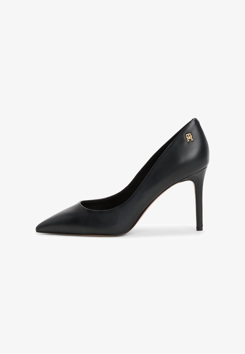Escarpin en cuir noir à talon haut avec bout pointu et logo doré sur le talon extérieur. Texture lisse, stiletto élancé et design élégant.