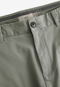 Uske slim fit hlače u maslinastozelenoj boji od mješavine pamuka. Imaju zatvarač s gumbićem, zip zatvaranje i tonirane šavove, a pružaju glatku i meku teksturu.