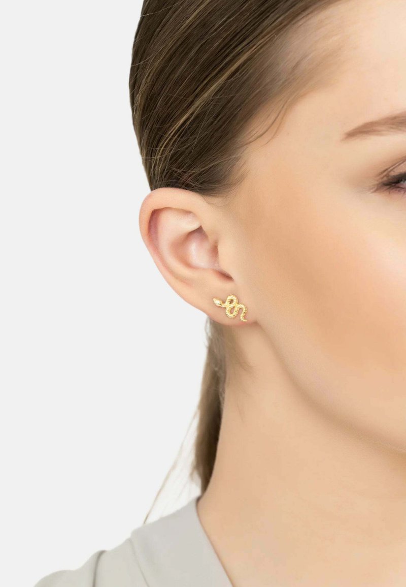 Orecchino a forma di serpente in oro con superficie texturizzata, indossato su un orecchio. Il design presenta curve e una finitura lucida.