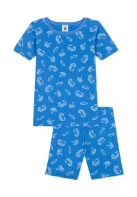 Ensemble de pyjama pour enfants bleu comprenant un haut à manches courtes et un short. Motif incluant des palmiers blancs, des planches de surf et des vans vintage. Tissu doux.