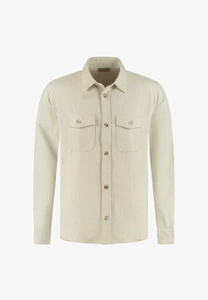 Pikkade varrukatega shirt heledast beežist tekstuuriga kangast. Omadused: nööpidega ees, kaks rinna-taskut ja beežid nööbid. Klassikaline lõikekujundus.