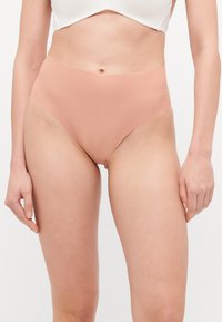 Bikiniji donji dio visoki struk u mekom breskvastom rebrastom materijalu, s glatkom teksturom i bez vidljivih metalnih dijelova ili ukrasa.