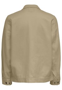 Beige jakke, tekstilstruktur med en jevn finish. Har krage, lange ermer og knappede mansjetter. Minimalistisk bakdesign uten synlig merking.