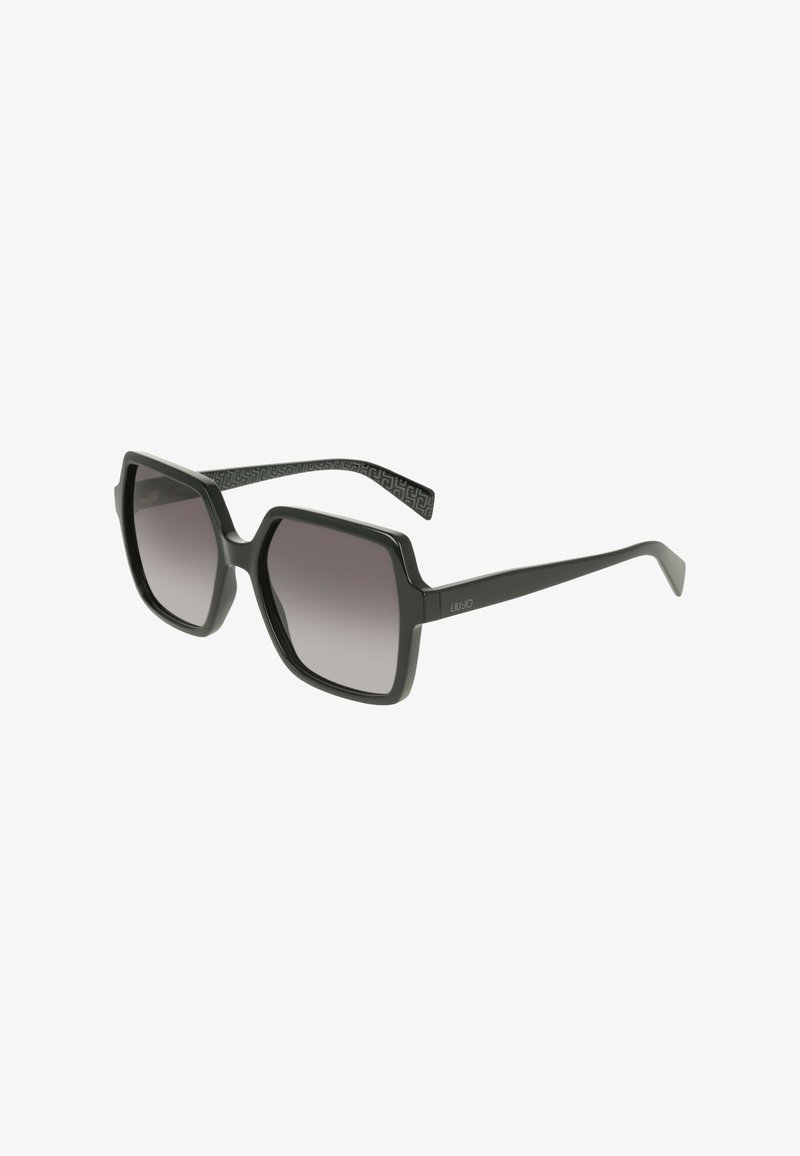 Lunettes de soleil carrées avec une monture noire épaisse et des verres dégradés foncés. Les branches présentent un motif texturé noir.