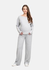 Completo da lounge grigio, morbido e largo, composto da una maglia con scollatura a barca e pantaloni a gamba larga; include tasche laterali e una cintura elastica.