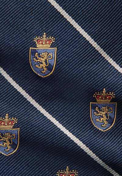 Gravata azul-marinho com riscas diagonais e bordado dourado de um emblema de leão dentro de um escudo, com uma coroa acima.