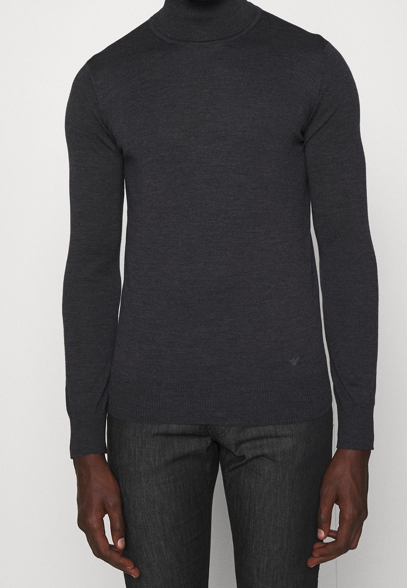 Pull à col roulé gris foncé en tissu doux, doté de manches longues et de poignets côtelés avec un détail de logo subtil à l'ourlet.