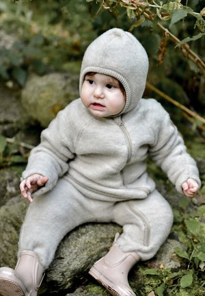 Grau melierter Fleece-Einteiler mit passender Kapuze, ausgestattet mit einem Reißverschluss vorne, gerippten Akzenten und beigefarbenen wasserdichten Stiefeln, auf einer strukturierten Oberfläche.