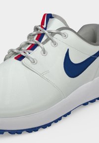 Λευκό αθλητικό παπούτσι Nike με μπλε λογότυπο, γκρι κορδόνια, γκρι γιακά και κόκκινη και μπλε ρίγα στη γλώσσα, εμφανιζόμενο από κοντινή γωνία.