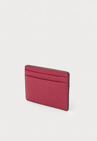 Rektangulær kortholder i teksturert magenta skinn, med fire kortspor på den ene siden og kontrasterende mørk kant langs kantene.