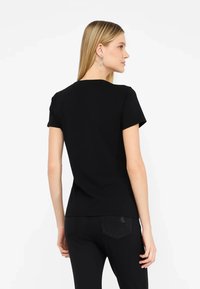 T-shirt nera a maniche corte con design semplice, realizzata in tessuto morbido. Presenta un collo rotondo e una forma aderente con orlo dritto.
