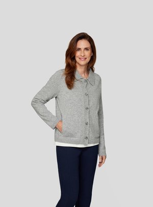 Gray knit cardigan with a rounded collar, button front, and long sleeves. Worn over a white shirt and paired with dark blue pants.