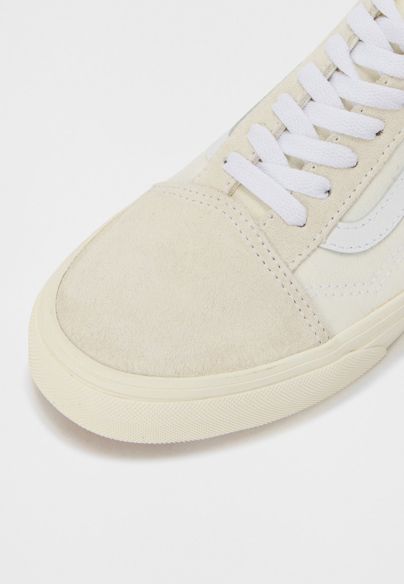 Beige Wildlederschuhe mit weißen Schnürsenkeln und dezentem Branding. Verfügt über eine strukturierte Gummisohle und einen glatten Lederstreifen an der Seite.