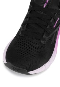 Pantof cu aspect sportiv, de culoare neagră, cu partea superioară din plasă, având accente roz și o talpă texturată. Șireturile și brandingul sunt vizibile clar pe lateral.