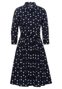 Vestido azul marino con un patrón geométrico blanco, que presenta un escote con collar, mangas largas, una cintura ceñida con cinturón y una falda con plisados.