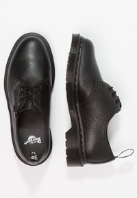Chaussures noires en cuir à lacets avec une finition texturée, bout arrondi et semelle plate en caoutchouc. Présentent une couture ton sur ton et une boucle à l'arrière du talon.