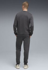 Dunkelgrauer Pullover und passende Jogginghosen aus einem weichen, strukturierten Stoff, mit gerippten Bündchen und einem lockeren Schnitt.