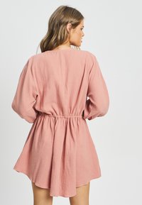 Roza, prozorna obleka z dolgimi rokavi, elastičnim pasom in razkošnim krilom, z enostavnim okroglim izrezom in teksturirano tkanino.