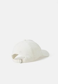White cotton baseball cap with a curved visor, stitched detailing, and an adjustable back strap with a metal buckle.