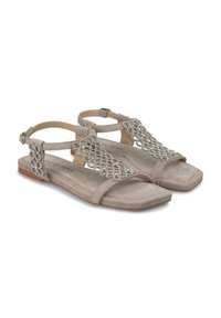 Sandalias de ante beige con suela plana, con cuentas plateadas decorativas en las correas y una hebilla en el tobillo para ajuste.
