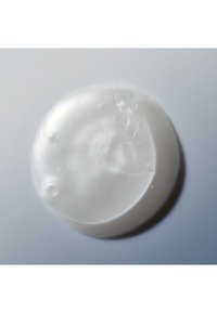 Klar, rund hvid sæbebar med glat overflade og let refleksion på en lys grå baggrund.