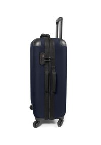 Námořnická modrá kufr s tvrdou skořepinou, výsuvným madlem, čtyřmi koly, černým zipem a popruhy a kombinovaným zámkem na boku.