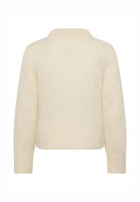Pulover v kremni barvi s kratkim krojem, rebrastim robom in dolgimi rokavi, z mehko teksturo in diskretnim vzorcem pletenja.