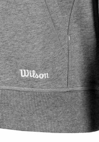 Grauer Sweatshirt mit geripptem Saum und Bündchen. Weißes "Wilson"-Logo, das auf der unteren linken Seite gestickt ist. Weicher Stoff.