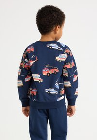 Felpa blu navy con stampe colorate di veicoli, inclusi camion dei pompieri e auto della polizia. Collo e polsini a costine, tessuto morbido.