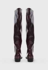 Knee-high, glossy burgundy boots made of shiny synthetic material, featuring smooth texture and a low black block heel.
