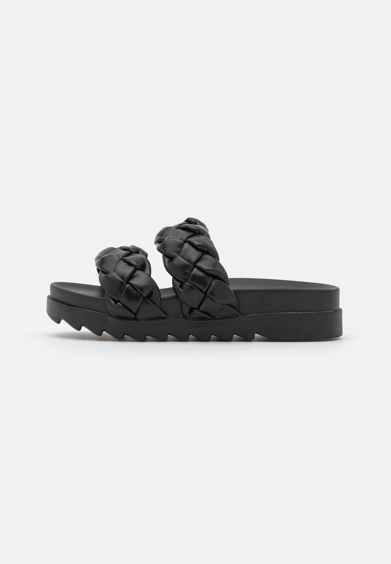 Sandales noires avec des brides tressées, dotées d'une semelle plate-forme épaisse et d'un motif de semelle en zigzag. Le matériau semble lisse et semblable à du cuir.