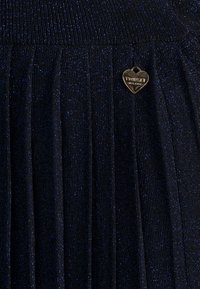 Mörkblå plisserad kjol i glänsande tyg, har en strukturerad yta och en liten hjärtformad Twisted Milano-logotyp.