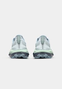 Vaaleansinisiä juoksukenkiä, joissa on teksturoitua verkkokangasta, heijastavia yksityiskohtia ja vihreät välipohjat; karkeat mustat ulkopohjat syvillä urilla.