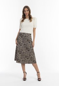 Hvid, ribbet kortærmet top parret med en knælang leopardprintnederdel. Nederdelen har et flydende A-linje design og sorte hæle.