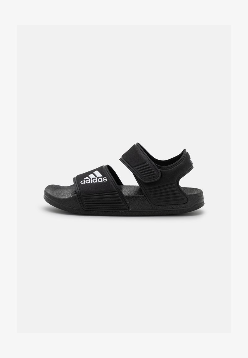 Black sandals featuring a textured strap with a Velcro closure, solid rubber sole, and contrasting white branding on the strap.