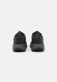 Schwarze Sportschuhe mit strukturiertem Mesh-Obermaterial, verstärktem Fersenbereich, Zuglasche und dämpfender Sohle, die Stabilität und Rutschfestigkeit bieten.
