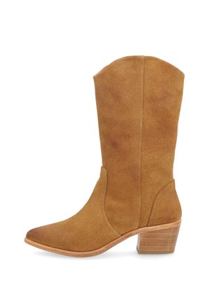 Buty typu western z jasnobrązowego zamszu do połowy łydki z szpiczastym noskiem i piętą z nakładanych drewnianych bloków, widziane od zewnątrz.