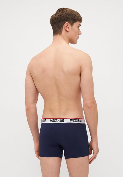 Navyfarbene Boxershorts aus glattem Stoff, mit einem kontrastierenden weißen Bund mit roten Akzenten und „MOSCHINO“-Branding.